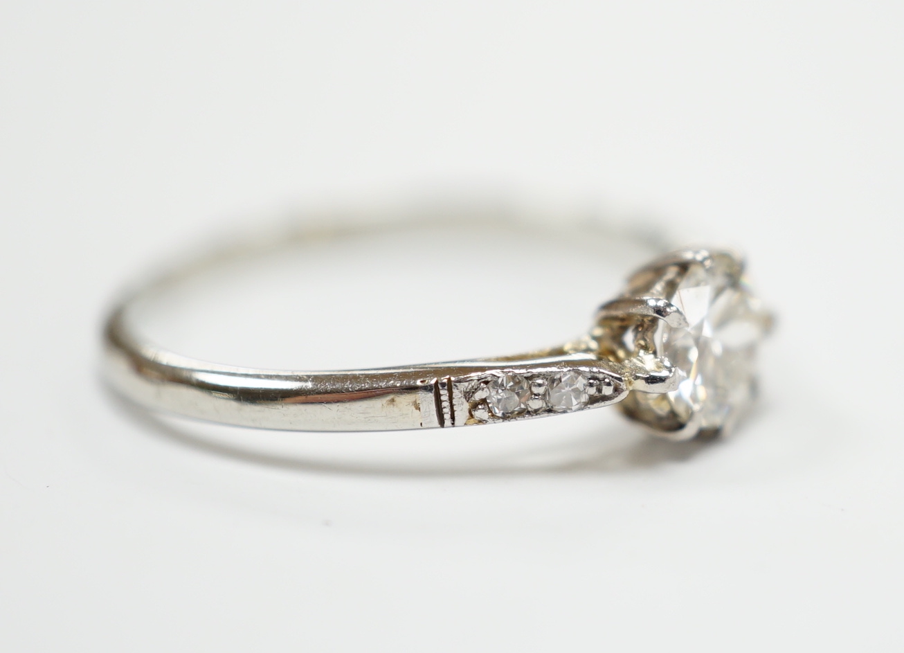 An 18ct, plat. and single stone diamond ring, with diamond set shoulders, size M/N, gross weight 1.9 grams.